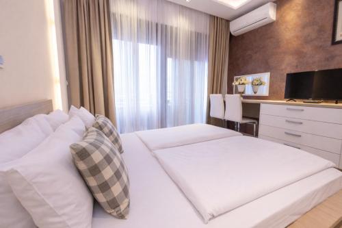 a hotel room with a white bed and a desk at Hotel Butua Residence in Budva