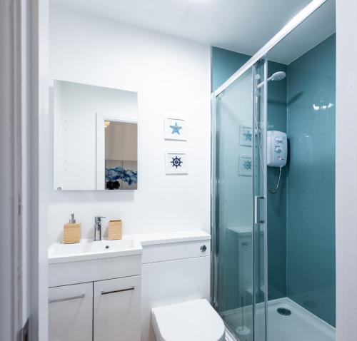 a bathroom with a shower and a toilet and a sink at Glan Neigr Apart-Hotel by Guestz in Rhosneigr
