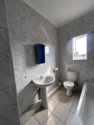 a bathroom with a sink and a toilet and a window at L-PACK PRIMROSe in Germiston