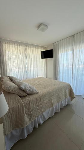 a bedroom with a bed with curtains and a television at Punta del Este, Sol y Luna II, Departamento 301 in Punta del Este
