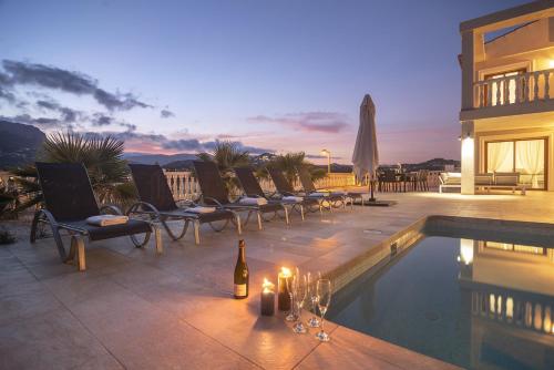 a patio with a bottle of wine next to a swimming pool at Villas Guzman - Grandiosa in Calpe