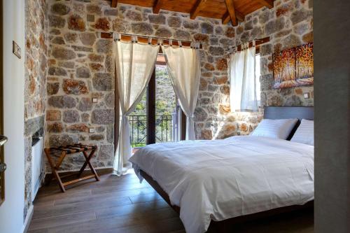 a bedroom with a bed and a stone wall at Elevi Mare Apartment in Tyros