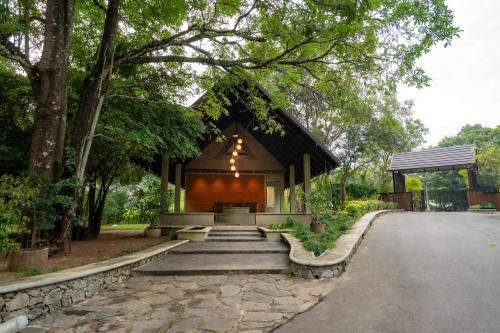 a small building with a black roof in a park at Trio Lodge- Habarana in Habarana