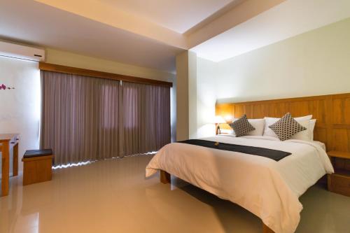 een slaapkamer met een groot bed en een groot raam bij AB Hotel Kuta in Kuta