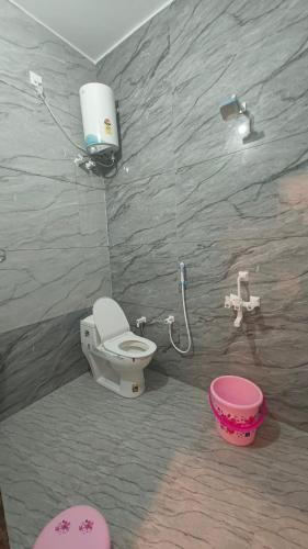a bathroom with a toilet and a pink bucket at Shree Karan Palace Family Guest House in Juliāsar