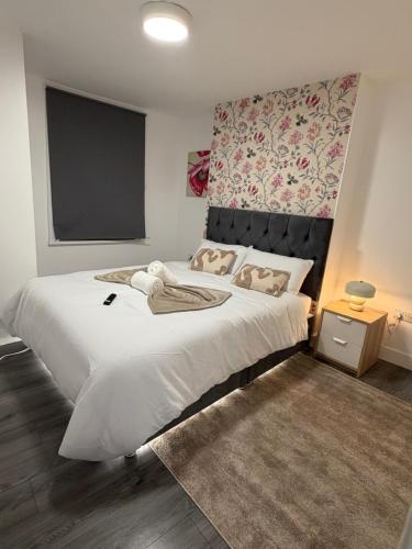 a bedroom with a large white bed with a floral headboard at Bpsairbnbltd in London