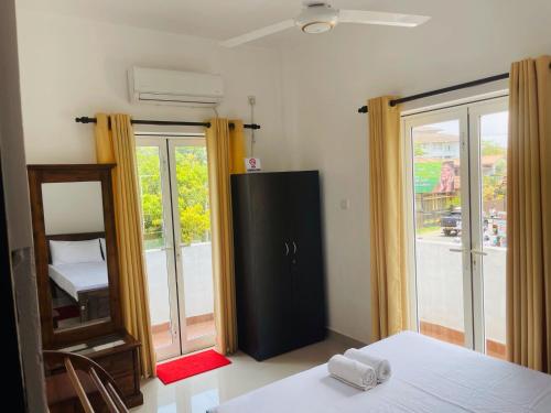a bedroom with a mirror and a black refrigerator at Liyasha Villa - AEONSKY in Negombo