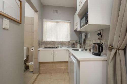 a small kitchen with white cabinets and a sink at The Old Stone House in Kloof