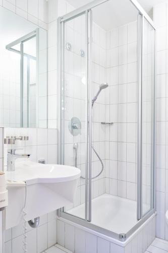 a white bathroom with a shower and a sink at Hotel Am Dom in Bamberg