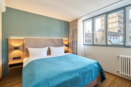a bedroom with a large bed with a blue blanket at Hotel Am Dom in Bamberg