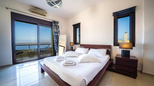 a bedroom with a bed with white sheets and windows at Villa Majestic Heated Pool Sauna & Endless Sea Views in Megála Khoráfia