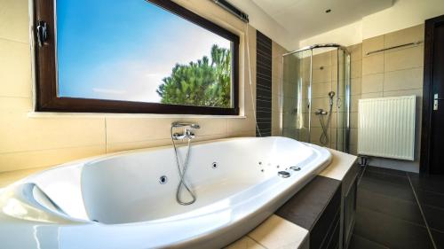 a large white tub in a bathroom with a window at Villa Majestic Heated Pool Sauna & Endless Sea Views in Megála Khoráfia
