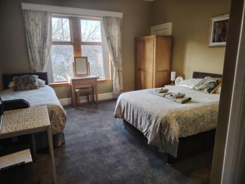 a bedroom with two beds and a window at Park Guest House in Inverness