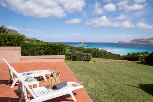 two white chairs sitting on a patio overlooking the ocean at Rocca Ruja Vip in Stintino