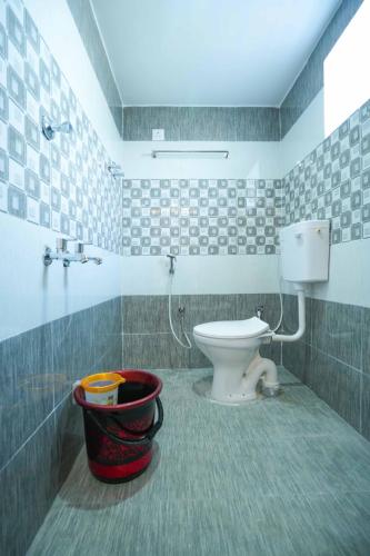 a bathroom with a toilet and a bucket in it at Ramnath Residency in Rāmeswaram