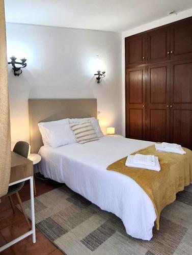 a bedroom with a large white bed and wooden cabinets at Quinta das AVES - Double Bedroom 1 in Odiáxere