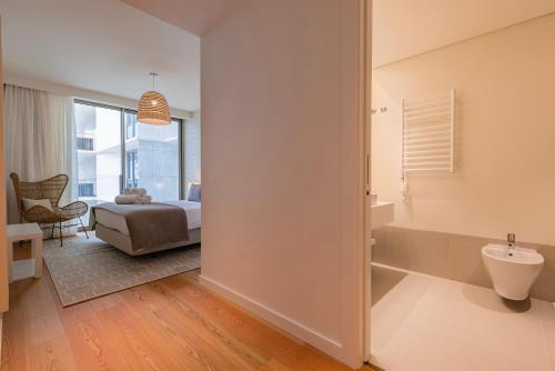 a bedroom with a bed and a bathroom with a sink at Bayline - Bezugo by Bedzy in Armação de Pêra