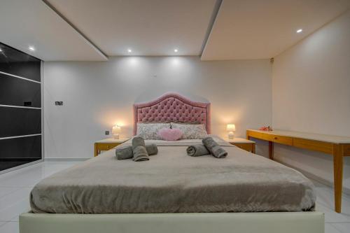 a bedroom with a large bed with a pink headboard at Unique - Spacious 3BR Premium Flat in Is-Swieqi