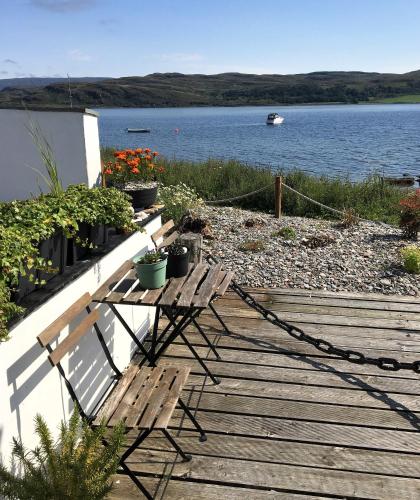 a couple of benches sitting on a boardwalk by the water at Pier Cottage at Kames in Kames