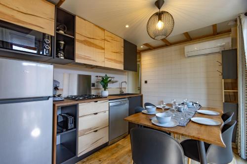 a kitchen with a table and chairs and a refrigerator at Les Chalets du Lac - Amnéville Cité des Loisirs Galaxie in Amnéville