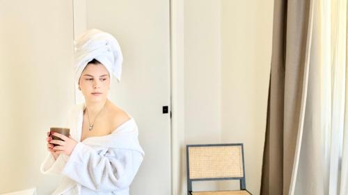 a woman with a towel on her head looking at her cell phone at Bayab Charming Rooms - Corso Garibaldi in Benevento