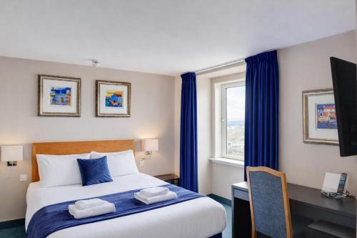 a bedroom with a bed and a desk and a window at Belvilla Aberdeen Bridge of Don Exhibition Centre in Aberdeen
