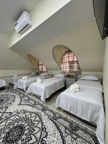 a room with three beds and a rug at Mansarda hostel in Samarkand