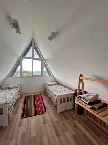a attic bedroom with two beds and a window at Selah Cabaña de dos habitaciones in Villa Las Rosas