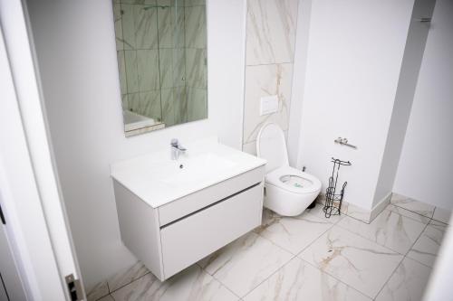 a white bathroom with a sink and a toilet at SoftStay Ellipse Luxury Apartment in Midrand