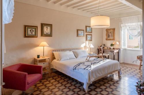 a bedroom with a bed and a red chair at La Dimora di Corte in Lucca