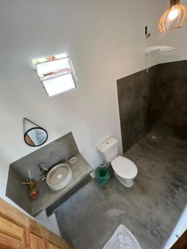 a bathroom with a toilet and a sink and a mirror at Suíte Adam 2 em Caraíva com Piscina 900m da Vila in Caraíva