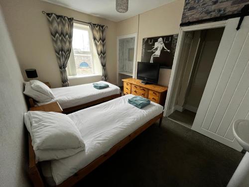 zwei Betten in einem kleinen Zimmer mit Fernseher in der Unterkunft The Innbetween in Pembroke Dock