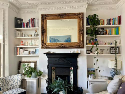 a living room with a fireplace and a mirror at Cosy Victorian house with free parking & fireplace in London