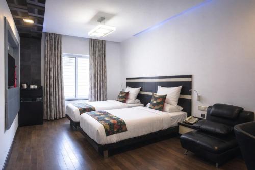 a hotel room with a bed and a chair at Purple Brigade, Bangalore in Bangalore