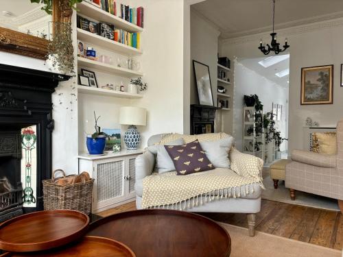 a living room with a couch and a chair at Cosy Victorian house with free parking & fireplace in London