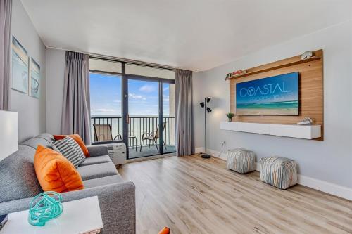 a living room with a couch and a tv at Oceanfront Suite, Seascape Sanctuary at OceanPark! 1104 in Myrtle Beach