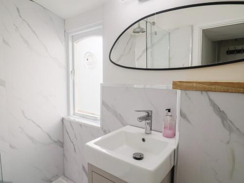 a white bathroom with a sink and a mirror at Riverdance Cottage in Lyme Regis
