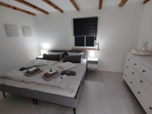 a white bedroom with a bed and a dresser at Ferienhaus Marion in Steinhagen