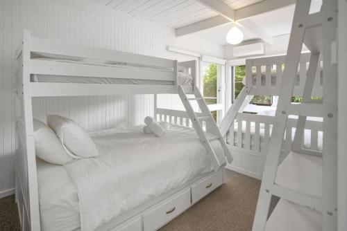 a bedroom with two bunk beds and a ladder at The Deck House in Lorne