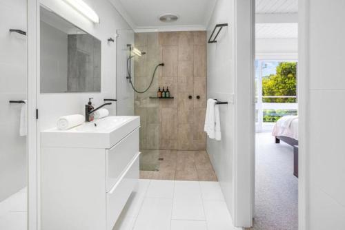 a white bathroom with a shower and a sink at The Deck House in Lorne