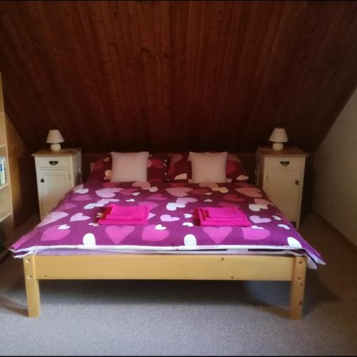 a bed with a purple comforter in a room at Chata v Poustce in Benecko