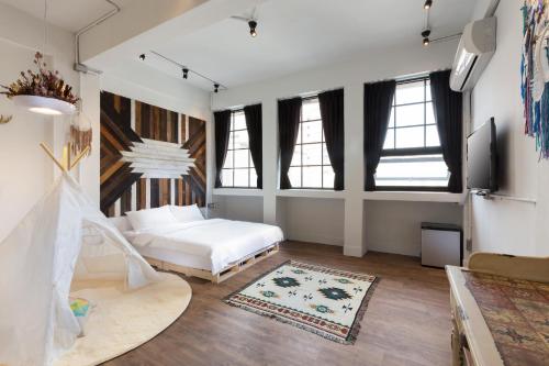 a bedroom with a bed and a couch and windows at You Worth Inn in Hualien City