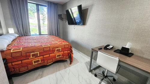 a bedroom with a bed and a desk with a phone at Hotel Fuego Bronx near Yankee Stadium in Bronx