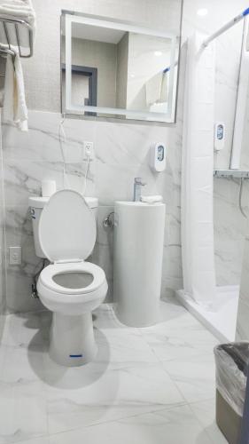 a white bathroom with a toilet and a mirror at Hotel Fuego Bronx near Yankee Stadium in Bronx