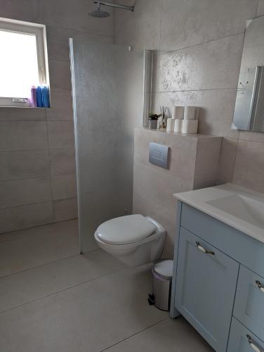a white bathroom with a toilet and a sink at הבית הכחול in Haspin