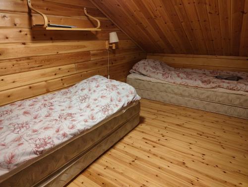 Zwei Betten in einem Zimmer mit Holzwänden und Holzböden in der Unterkunft Suomunkutsu 2 in Suomutunturi