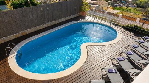a swimming pool on a wooden deck with lounge chairs at Villa Med A 2 kilometros andando de la playa, del puerto de Aguadoç y a 4 del centro de Sitges Muy Soleada todo el dia Capacidad superior a 16 personas NO REQUIERE COCHE in Sitges
