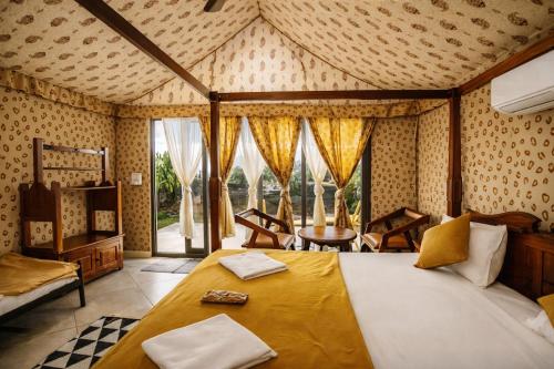 a bedroom with a large bed in a room with windows at Amber Resort in Sasan Gir