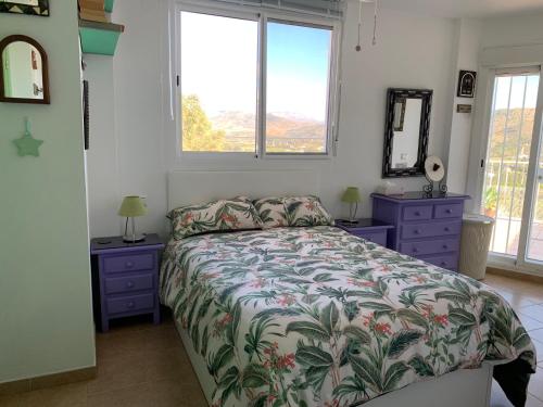 a bedroom with a bed and two night stands and two windows at One bedroom penthouse in Alora