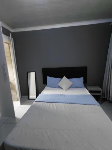 a bedroom with a white bed with blue pillows at Mama R's Budget-friendly BACKROOM 3 in Newcastle